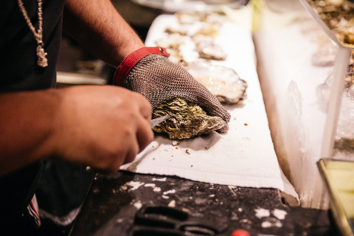 Man shucking oyster with glove on